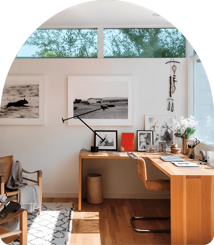 A room with a desk, chair and pictures on the wall.